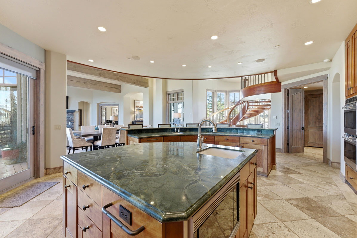 Gourmet kitchen with stone countertops, integrated sink, custom wood cabinetry, and stainless steel double ovens