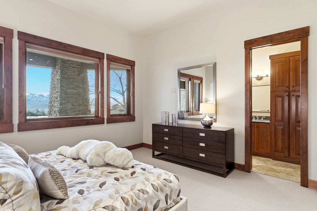 Room featuring multiple large windows with wood-finish trim, offering expansive exterior scenery including distant mountains and a stone architectural element