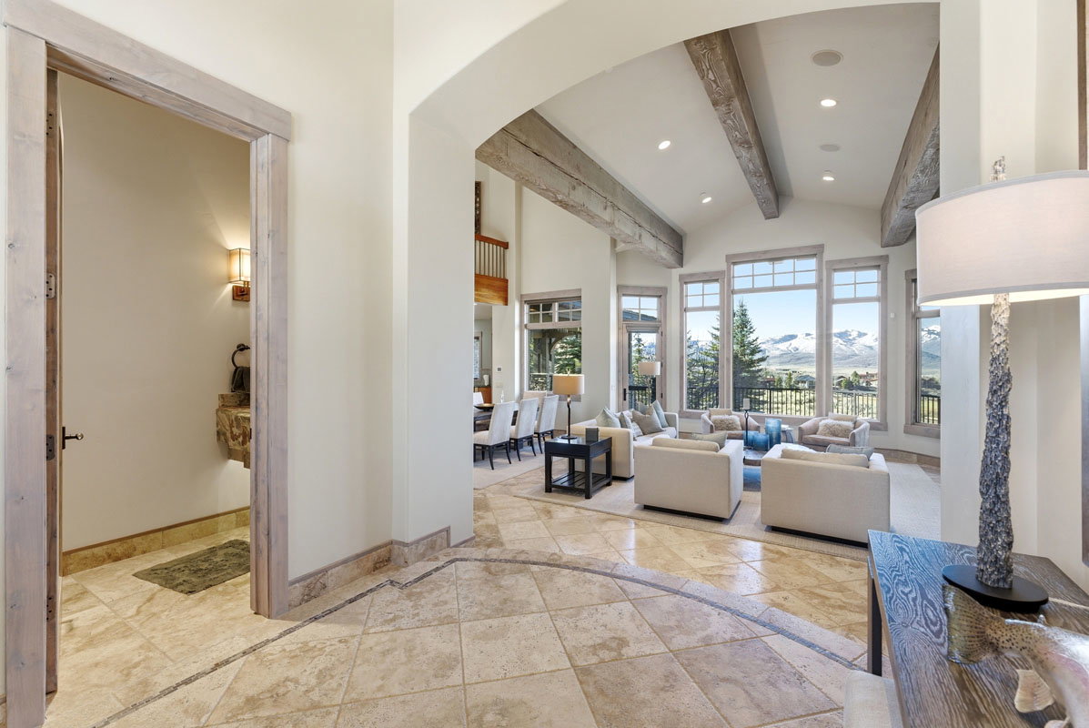 Vaulted ceiling living room featuring exposed wood beams, extensive window array, recessed lighting, and tiled flooring