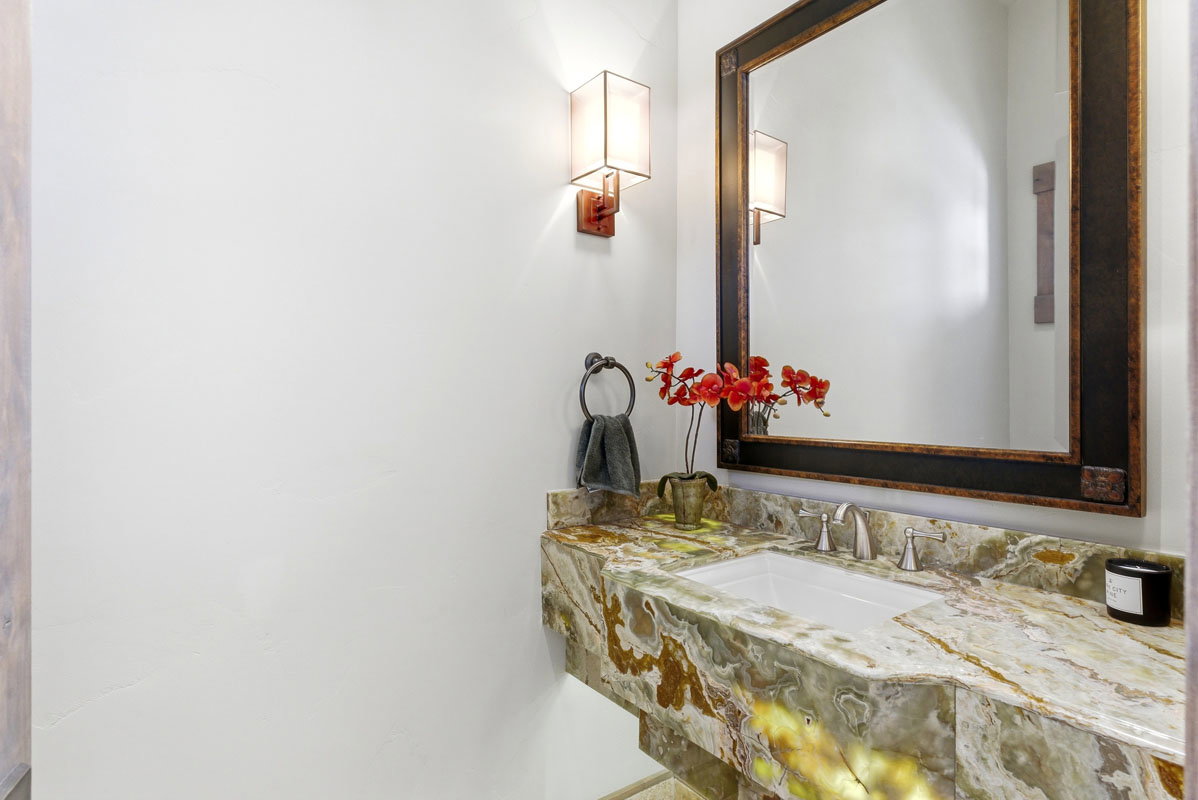 Vanity featuring a green and brown veined countertop with an undermount sink, brushed nickel faucet, and a large framed mirror