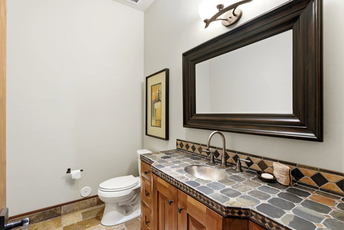 Vanity featuring a mosaic tile countertop, undermount sink, and wood cabinetry