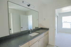 Spacious bathroom vanity featuring a rectangular under-mount sink, dark countertop, and chrome faucet