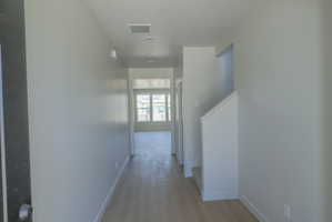 Hallway featuring light wood-finish flooring, neutral wall paint, and a staircase with white risers