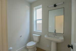 Modern powder room featuring a pedestal sink, rectangular mirror with a black frame, and a contemporary wall-mounted light fixture
