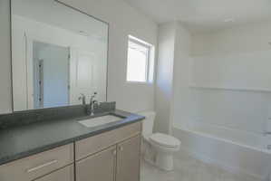 Bathroom with a light-toned vanity, integrated sink, and dark countertop