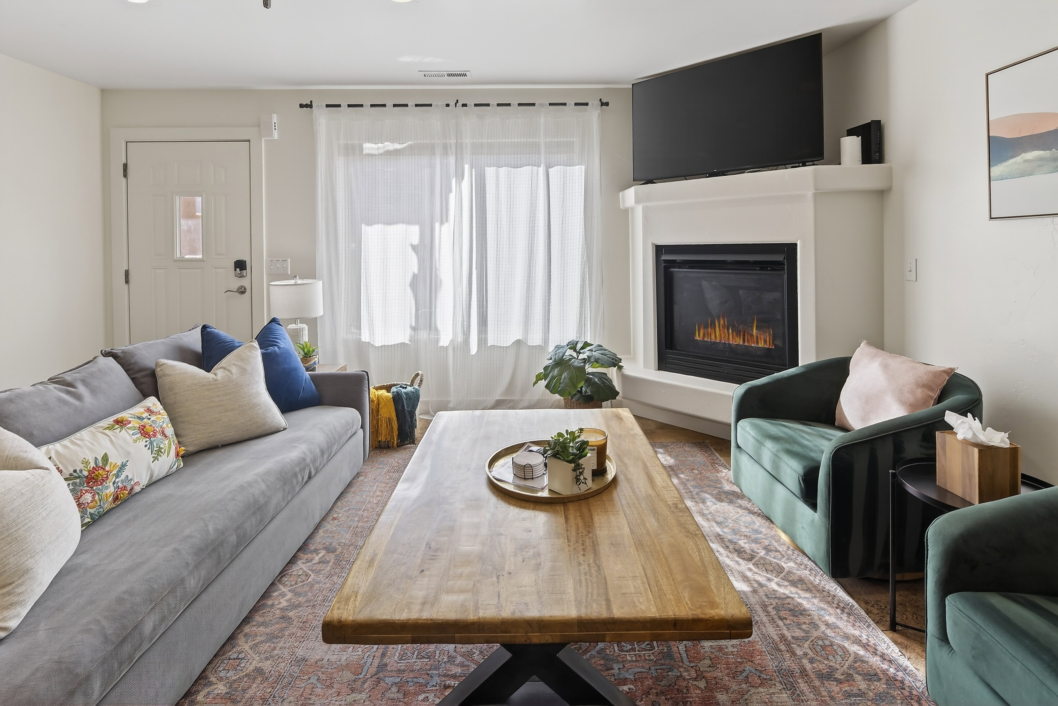 Living area featuring a corner fireplace with a white mantel, an entryway door with a small window, and wood-finish flooring