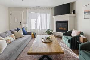Living area featuring a corner fireplace with a white mantel, an entryway door with a small window, and wood-finish flooring