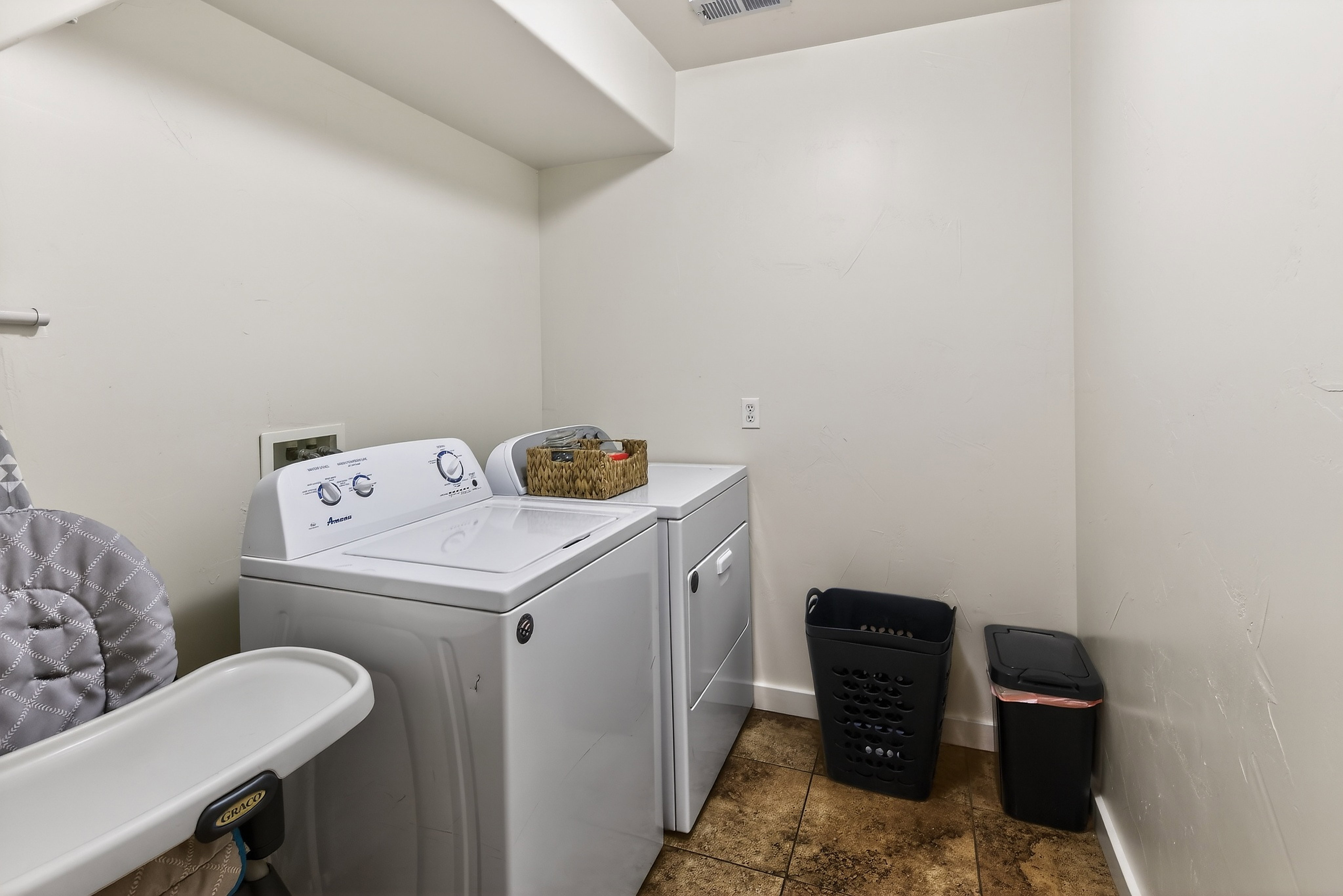 Dedicated laundry area featuring a washer and dryer set, overhead shelving, and neutral wall finishes