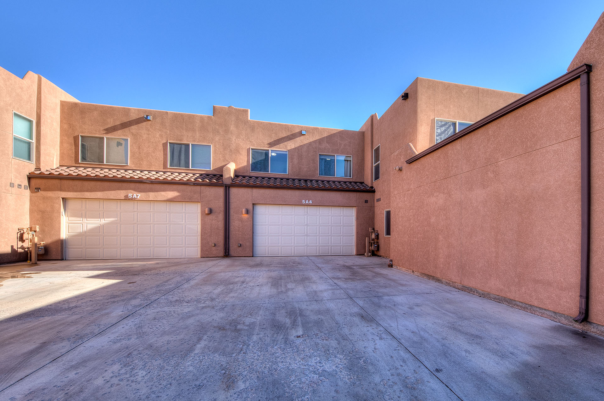 Stucco exterior with multiple garage bays, covered entries, and upper-level windows