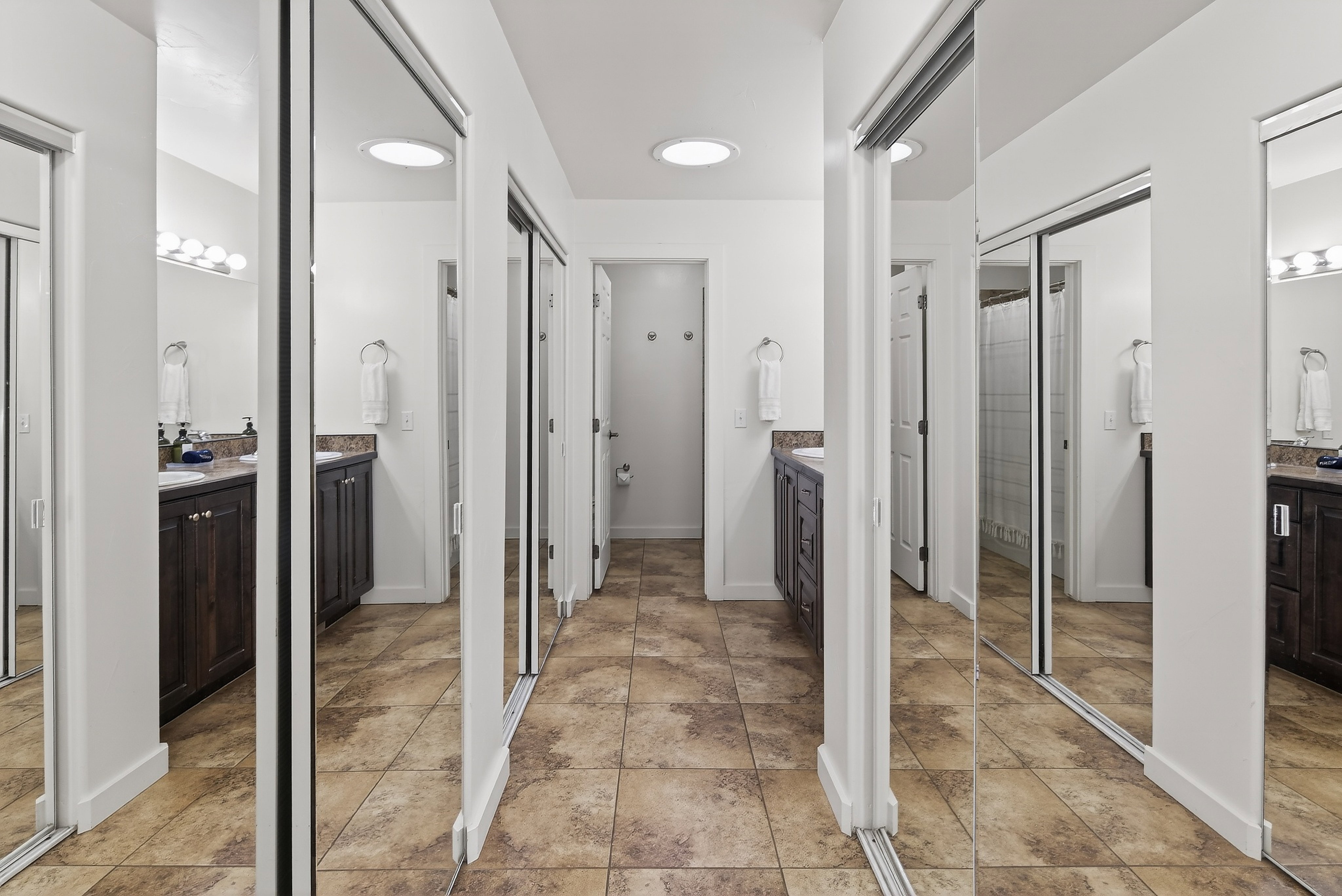 Hallway featuring tile flooring, mirrored closet doors, recessed lighting, and access to additional spaces