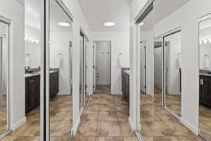 Hallway featuring tile flooring, mirrored closet doors, recessed lighting, and access to additional spaces