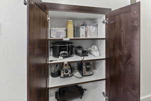 Built-in pantry cabinet featuring rich wood-finish doors, interior shelving, and a bright white interior finish