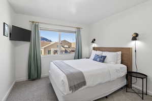 Bedroom featuring a large window, wall-mounted television, and sconce lighting