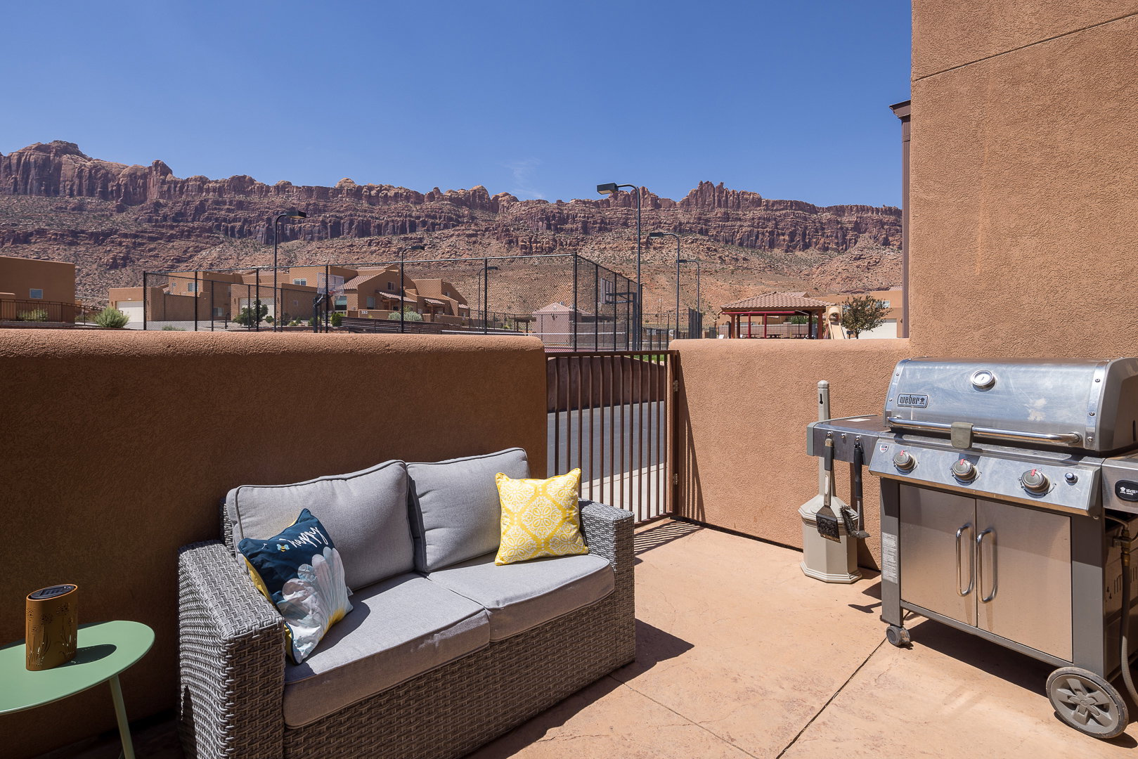 Private patio space featuring a concrete surface, stucco half-wall, and metal gate