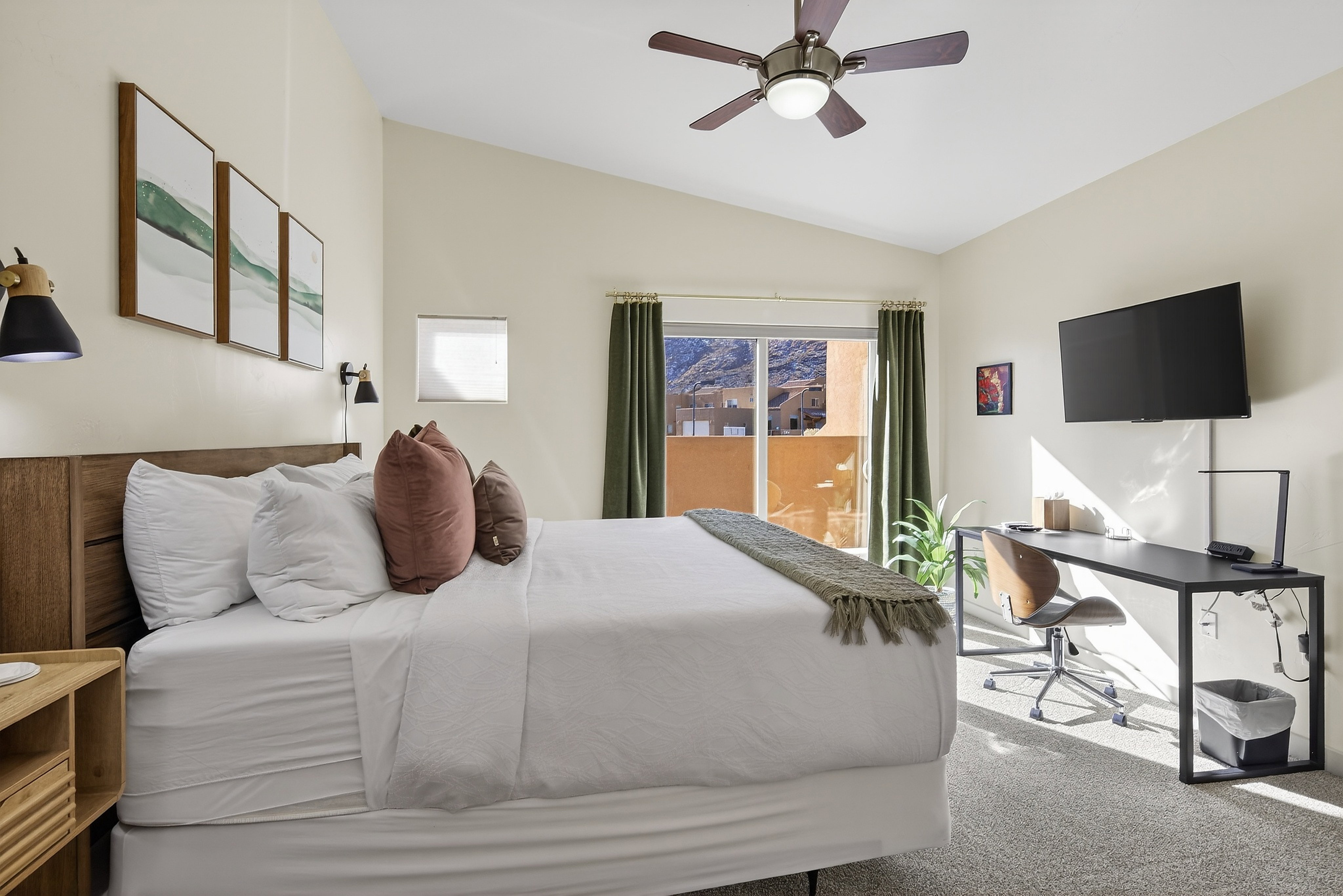 Bedroom featuring a vaulted ceiling with a ceiling fan, wood-finish headboard, built-in sconce lighting, and a sliding glass door