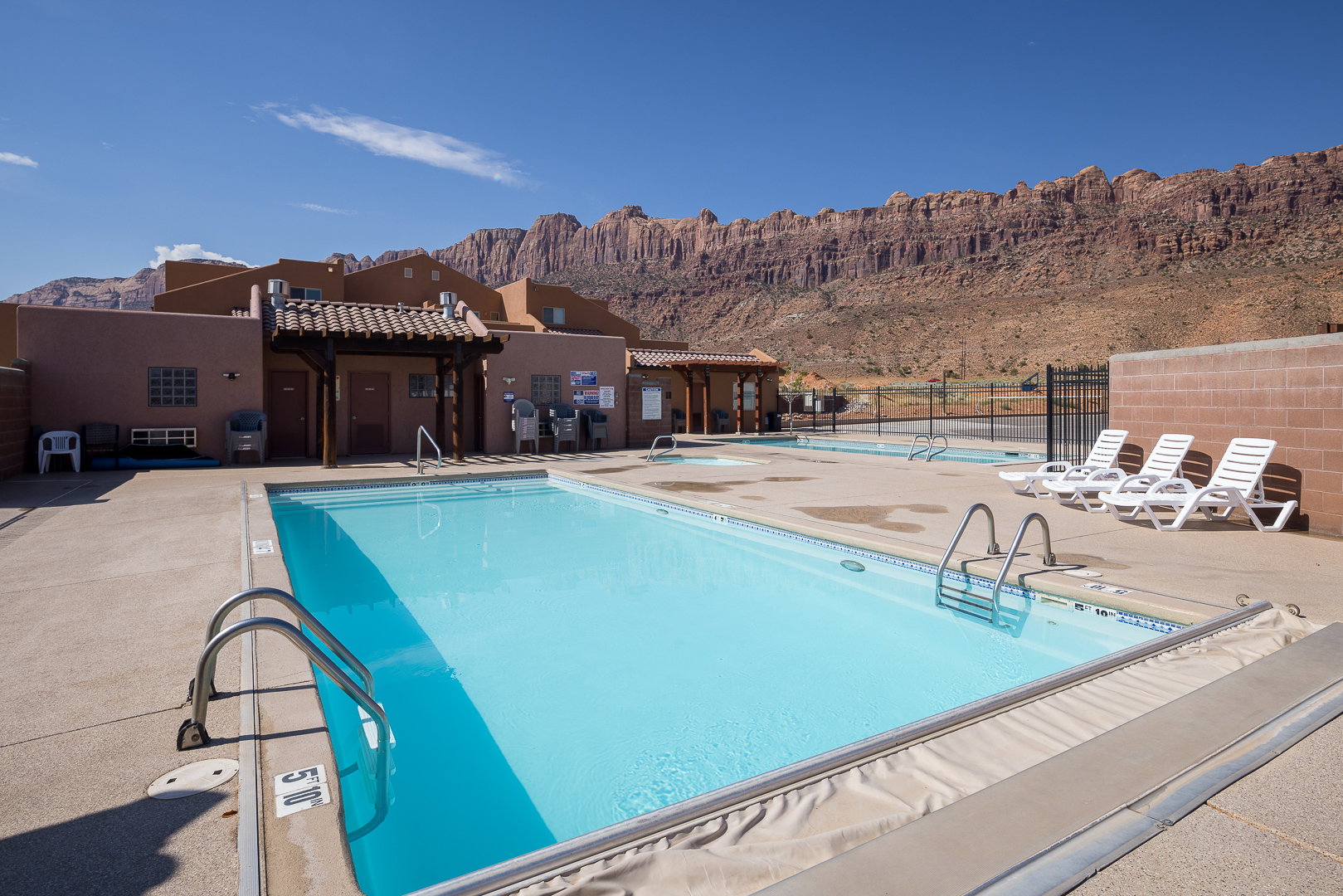 Outdoor swimming pool with integrated steps, concrete surround, adjacent spa, and a distant mountain backdrop