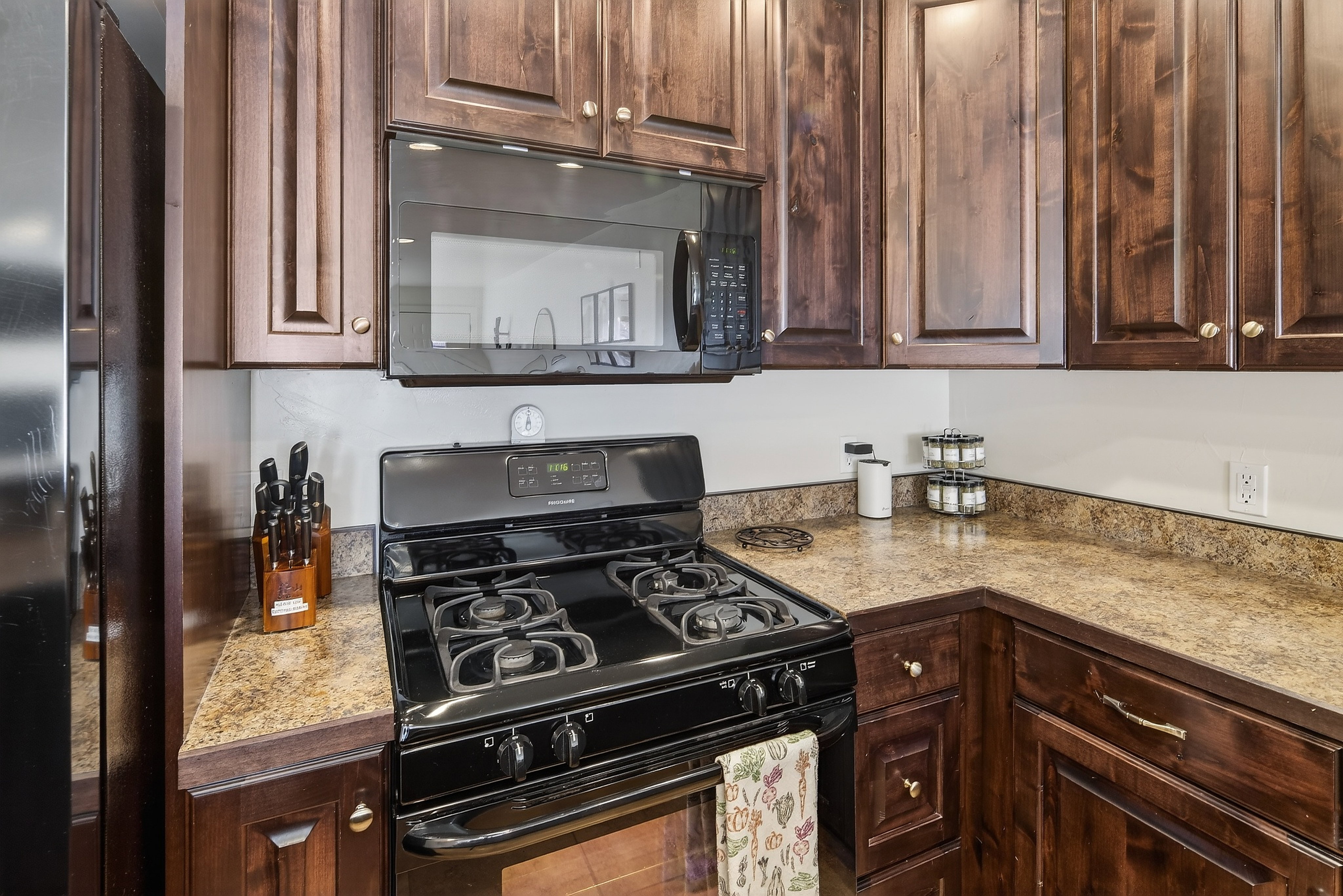 Kitchen featuring dark wood cabinetry, an over-the-range microwave, a gas range with four burners, and light-toned countertops