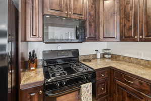 Kitchen featuring dark wood cabinetry, an over-the-range microwave, a gas range with four burners, and light-toned countertops