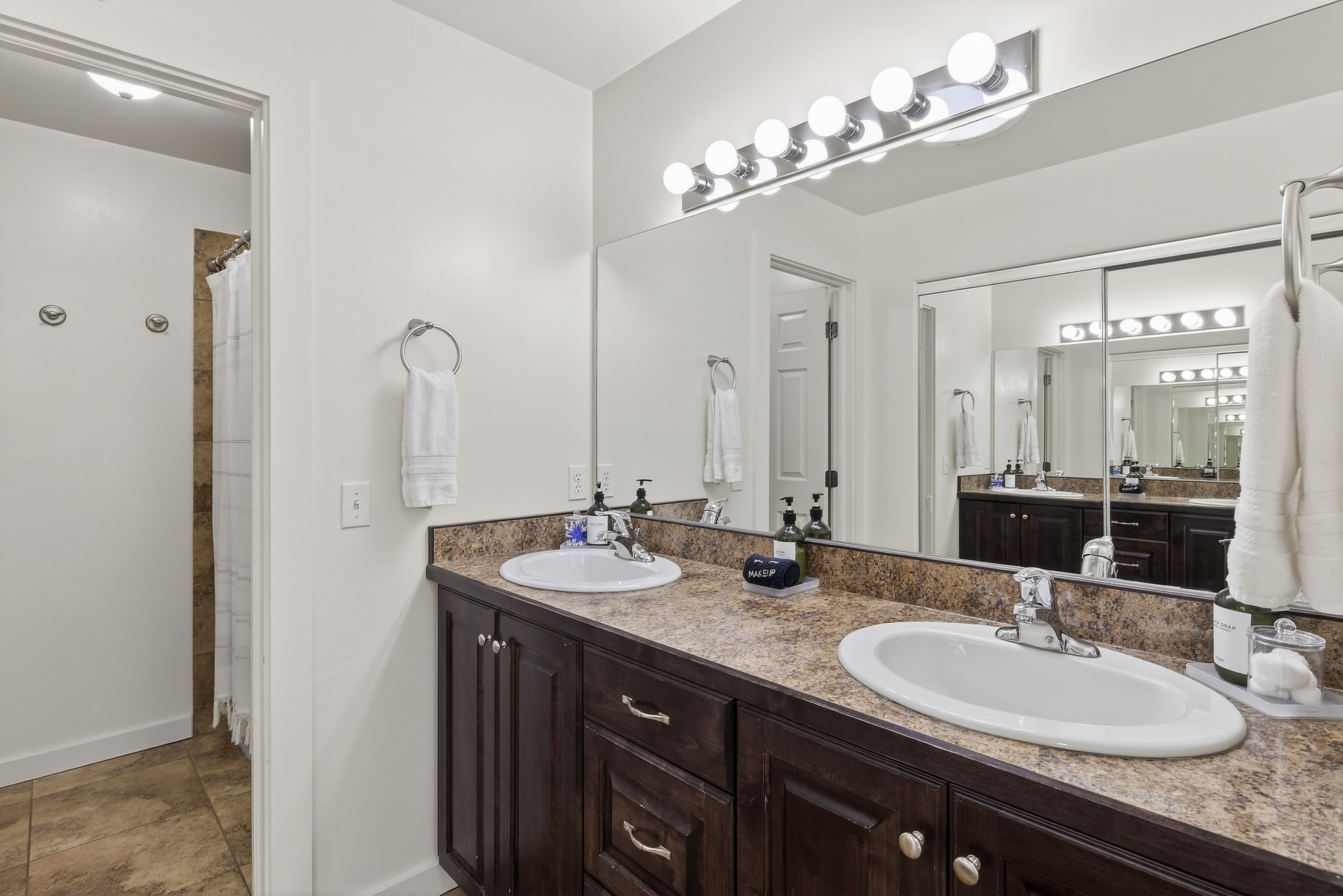 Double vanity featuring dark wood-finish cabinetry, integrated oval sinks, and a textured countertop