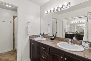 Double vanity featuring dark wood-finish cabinetry, integrated oval sinks, and a textured countertop