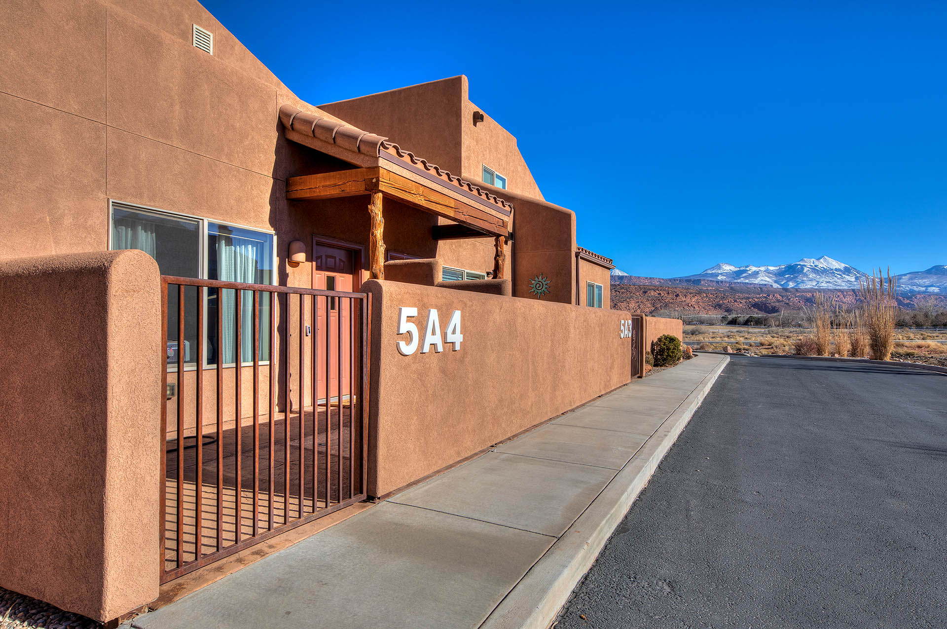 Southwestern-style stucco exterior with a tile-roofed entryway featuring natural wood beams and log supports