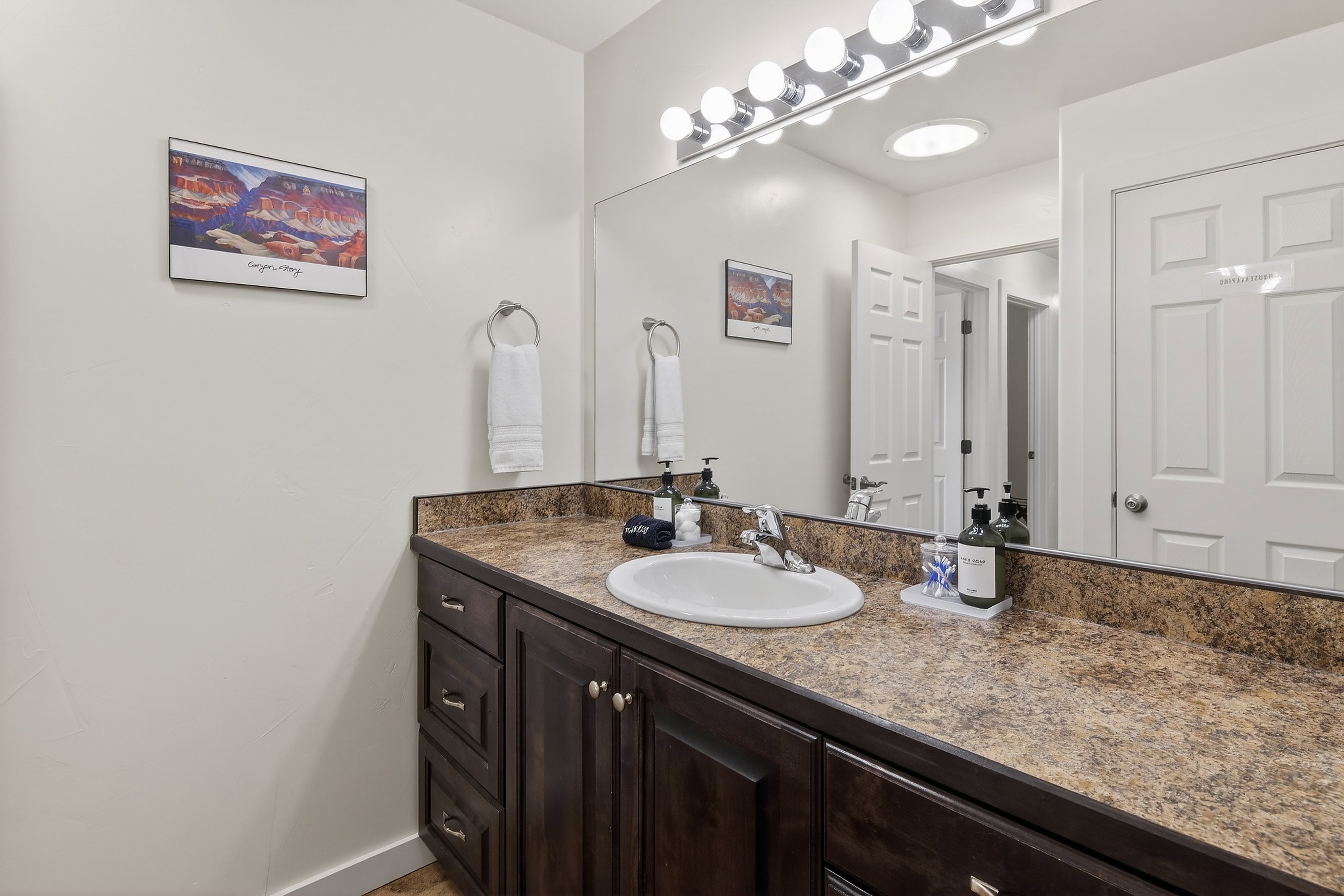 Bathroom vanity featuring a single basin sink, laminate countertop, and wood-finish cabinetry
