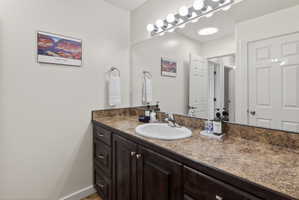 Bathroom vanity featuring a single basin sink, laminate countertop, and wood-finish cabinetry