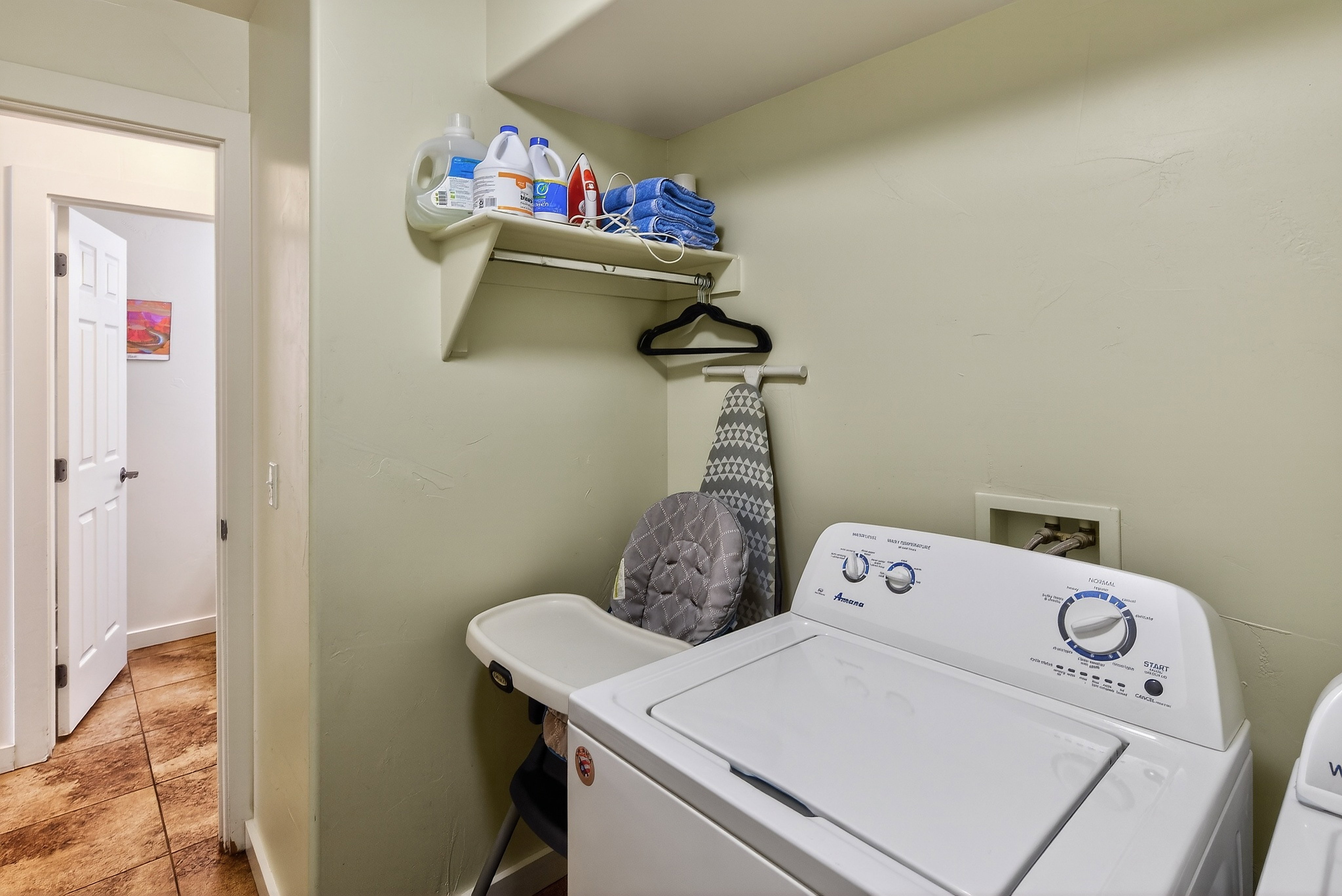 Dedicated laundry area featuring a wall-mounted shelf, integrated hanging rod, and textured wall finish