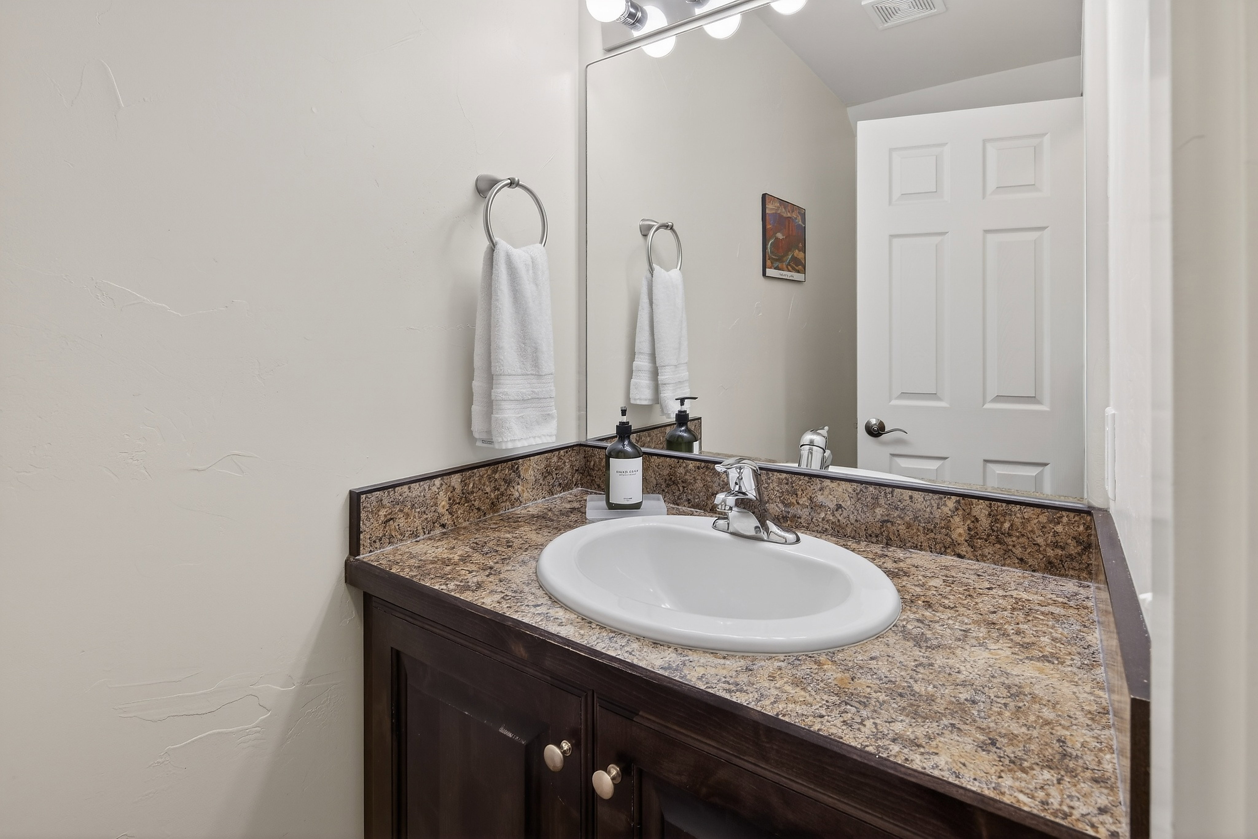 Bathroom vanity featuring a speckled countertop, an undermount sink, and a chrome faucet