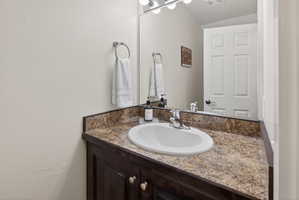 Bathroom vanity featuring a speckled countertop, an undermount sink, and a chrome faucet