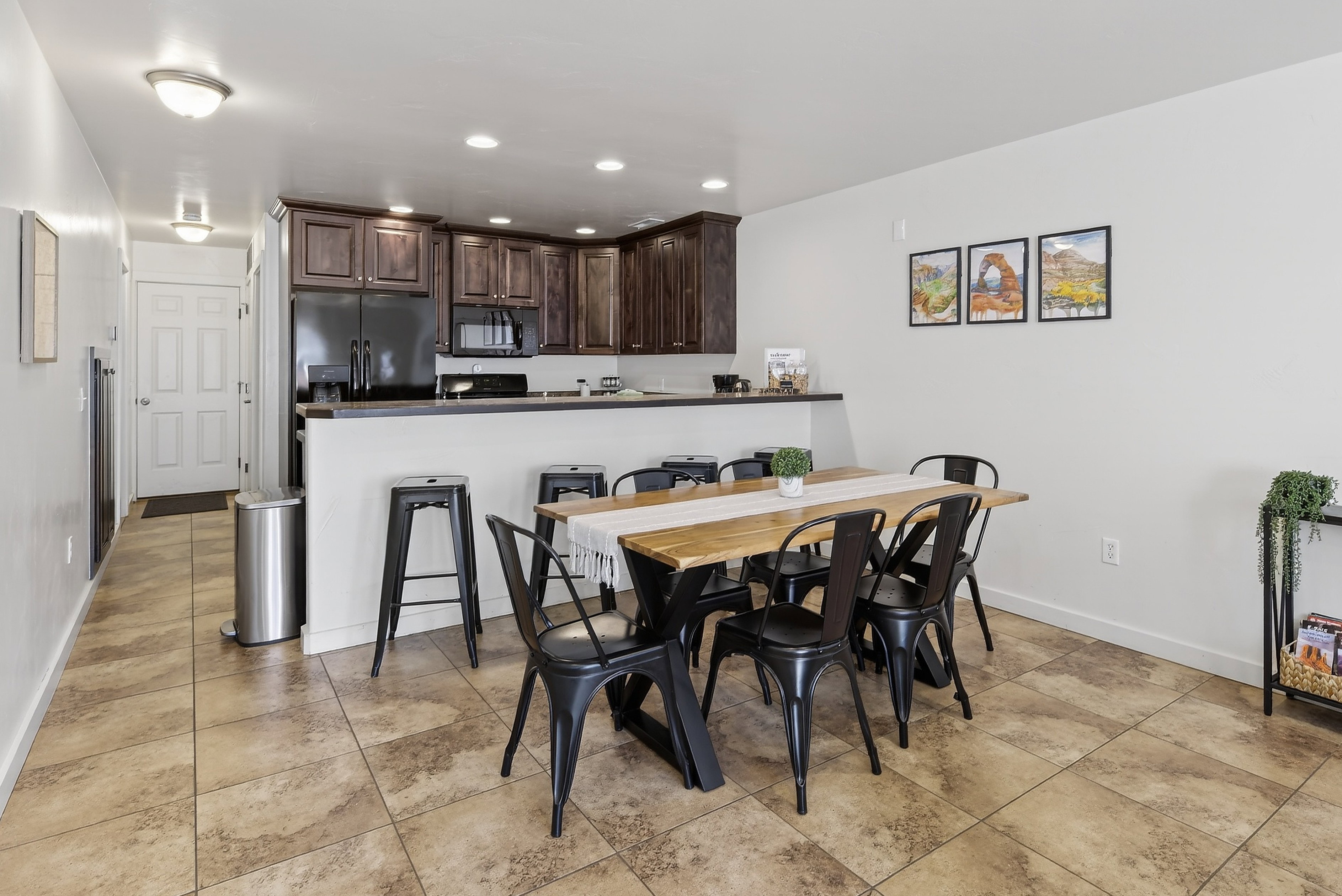 Open-concept living area featuring a kitchen with dark wood-finish cabinetry, black appliances, and a breakfast bar
