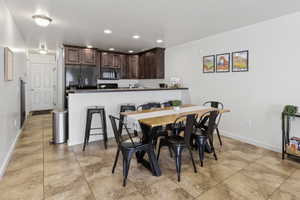 Open-concept living area featuring a kitchen with dark wood-finish cabinetry, black appliances, and a breakfast bar
