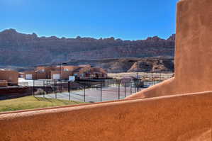 Outdoor sports court with fencing, surrounded by stucco residential structures featuring attached garages