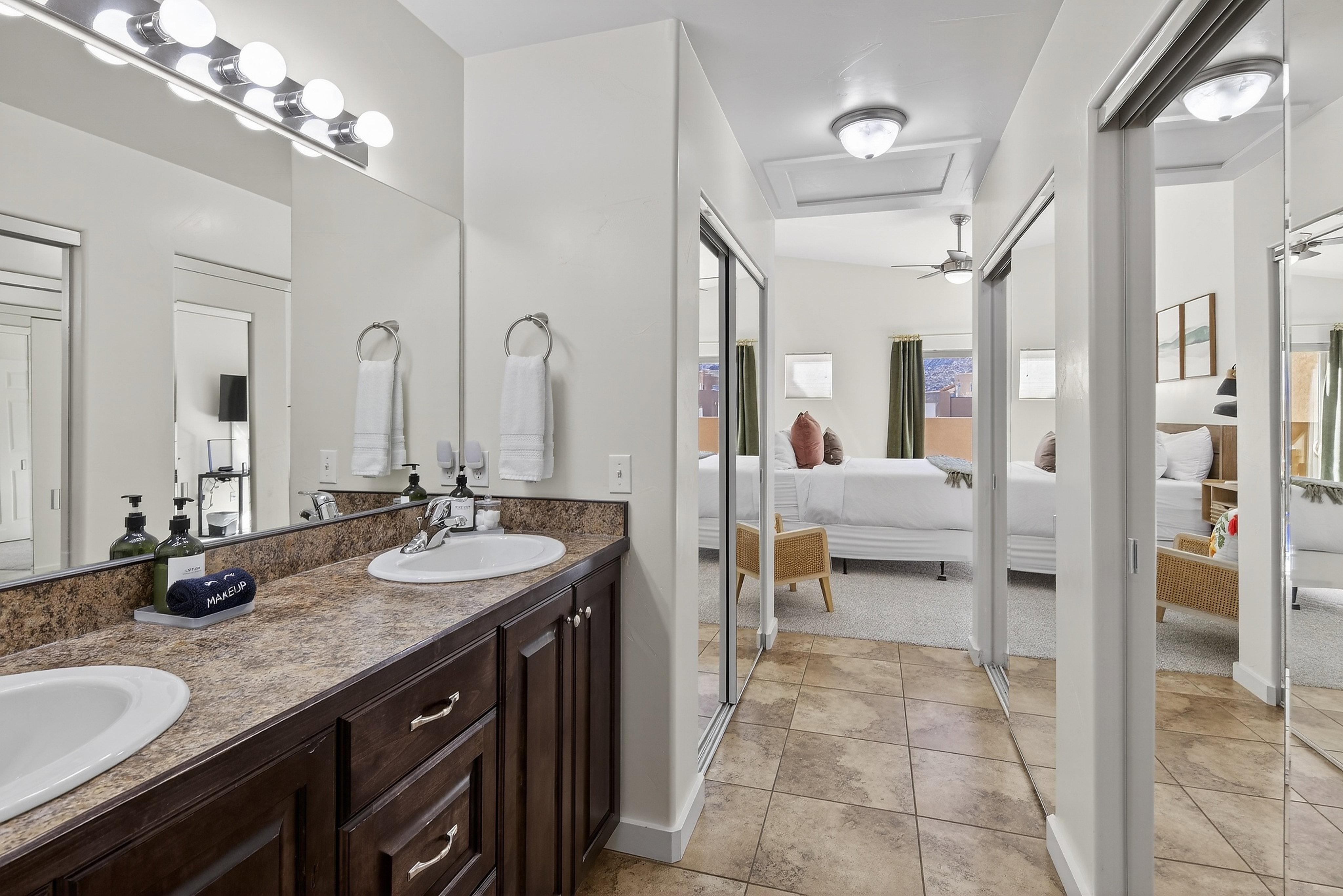 Dual vanity with dark wood-finish cabinetry, integrated sinks, and a speckled countertop