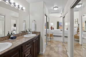 Dual vanity with dark wood-finish cabinetry, integrated sinks, and a speckled countertop