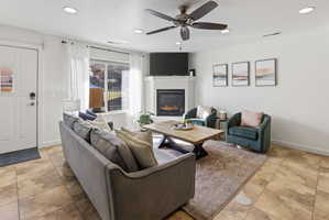 Living area featuring a fireplace with a white mantel, recessed lighting, and a ceiling fan