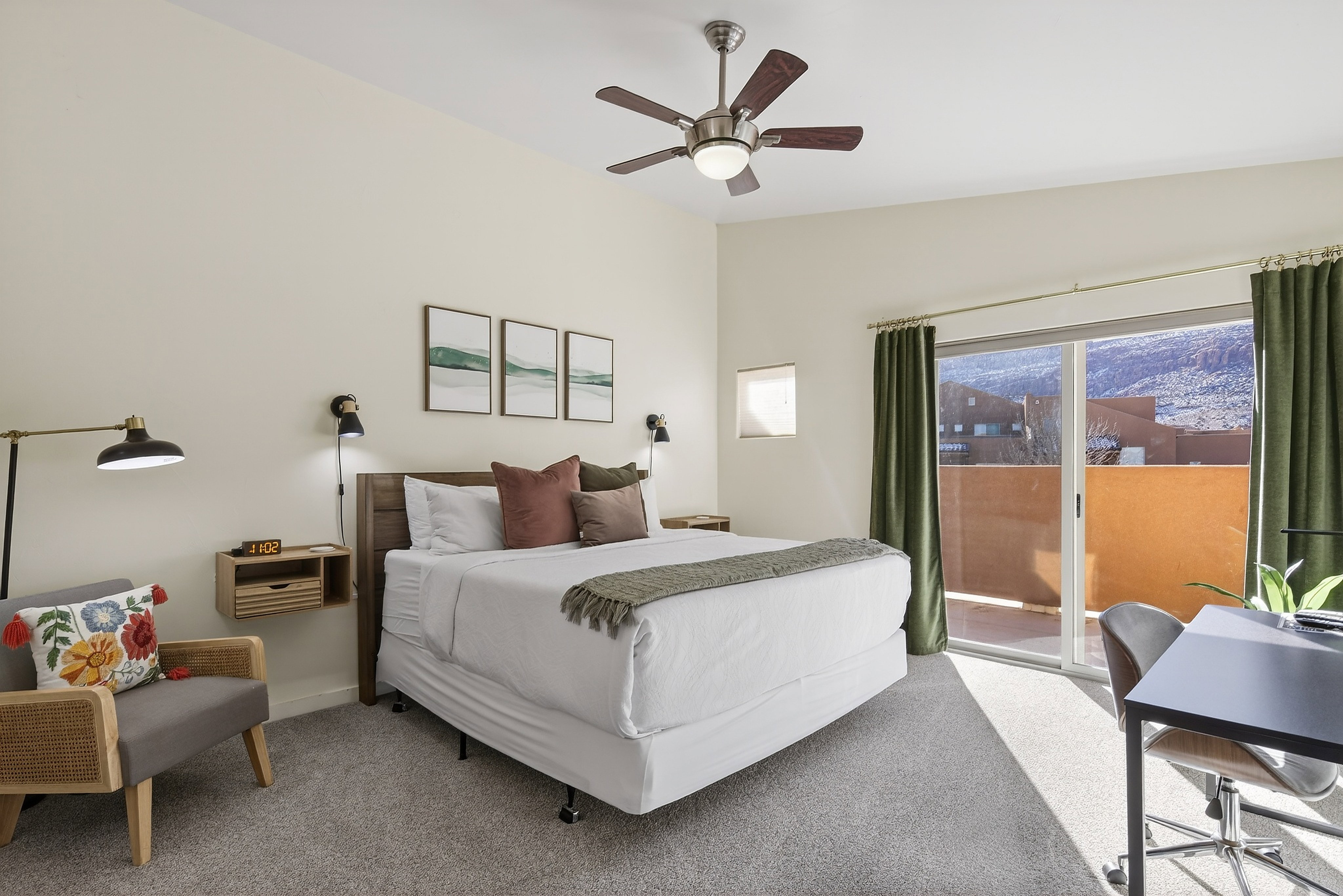 Bedroom featuring a sliding glass door to an outdoor area, a ceiling fan with integrated lighting, wood-finish headboard, and wall-mounted sconce lighting