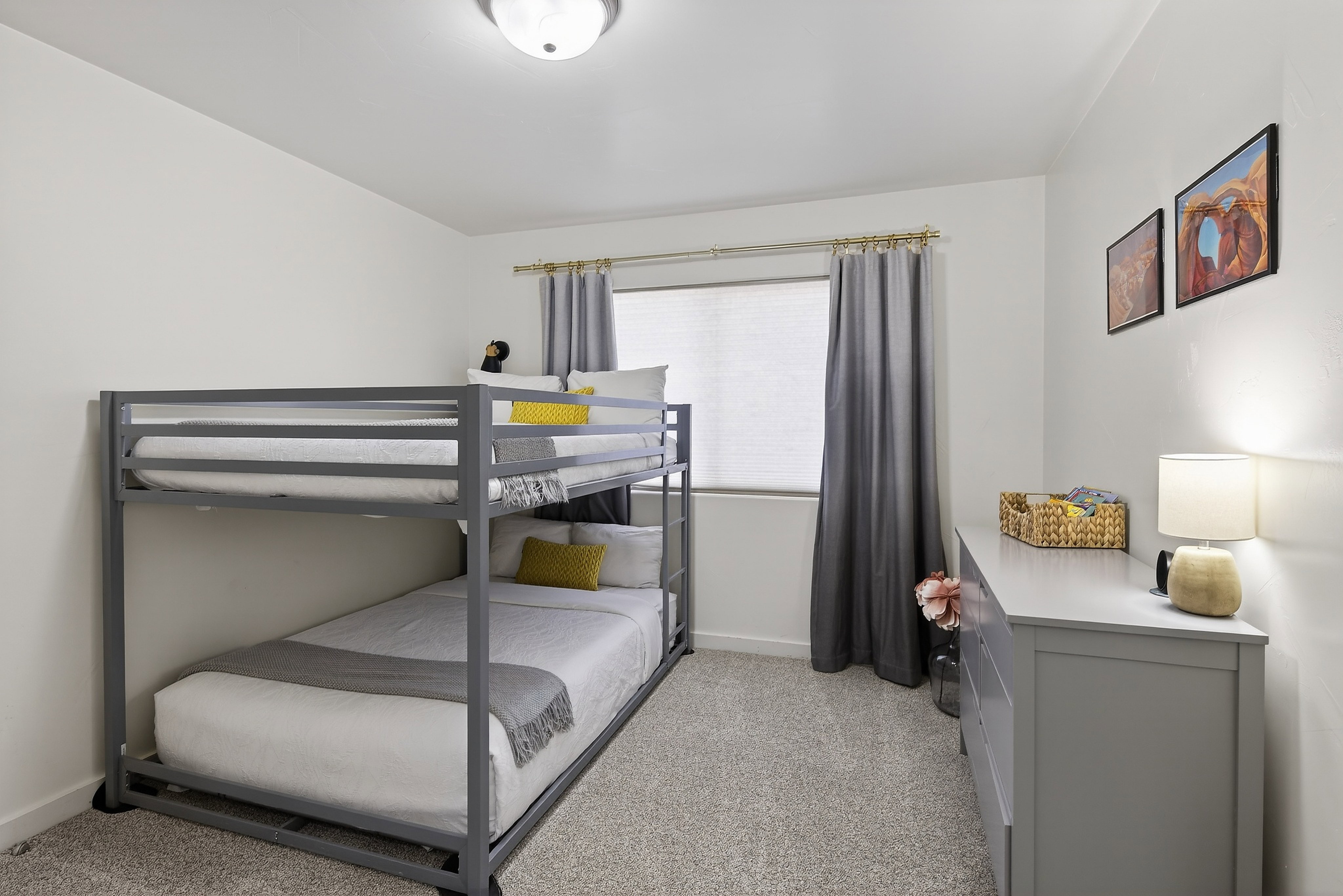 Carpeted bedroom featuring white walls, a single window with blinds, and a flush-mount ceiling light fixture