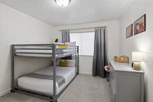 Carpeted bedroom featuring white walls, a single window with blinds, and a flush-mount ceiling light fixture