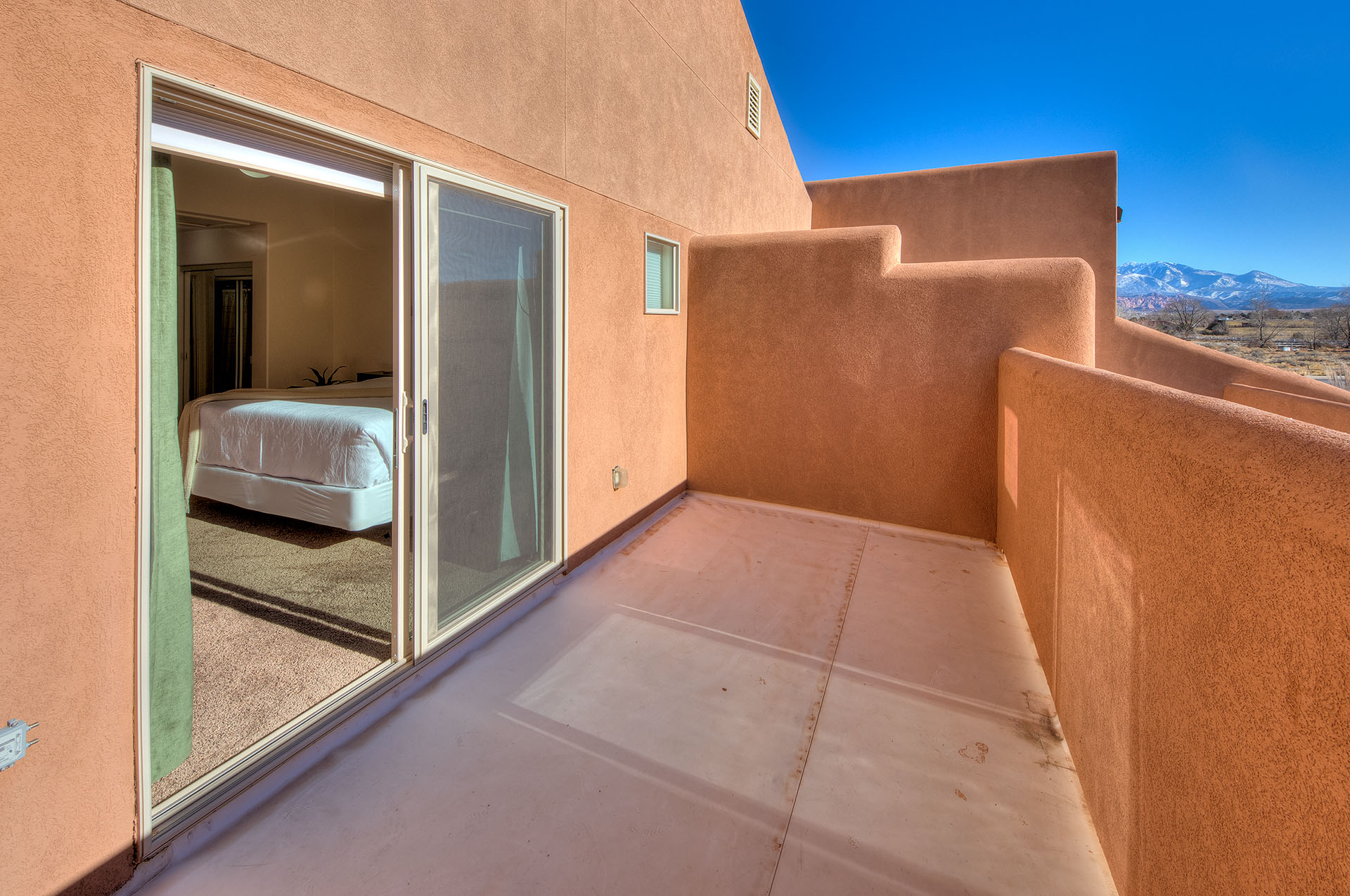 Private outdoor patio featuring a stucco exterior, sliding glass door, and distant mountain scenery