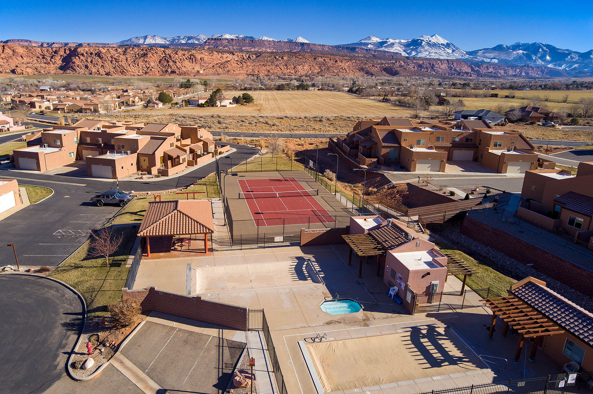 Community amenities featuring a tennis court, a covered outdoor pavilion, and a swimming pool area with a spa