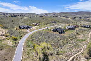 Expansive hillside setting featuring multiple residences on winding roads, surrounded by natural shrubland and distant mountain ranges
