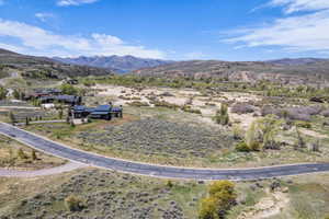 Expansive property featuring a paved road, natural shrubbery, and distant mountainous terrain