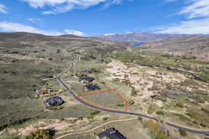 Expansive parcel featuring a paved road frontage, surrounded by natural landscaping, with distant mountains and a body of water visible on the horizon