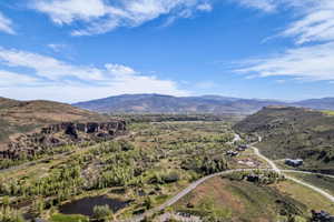 Expansive mountain landscape featuring a river valley, mature trees, and multiple residences