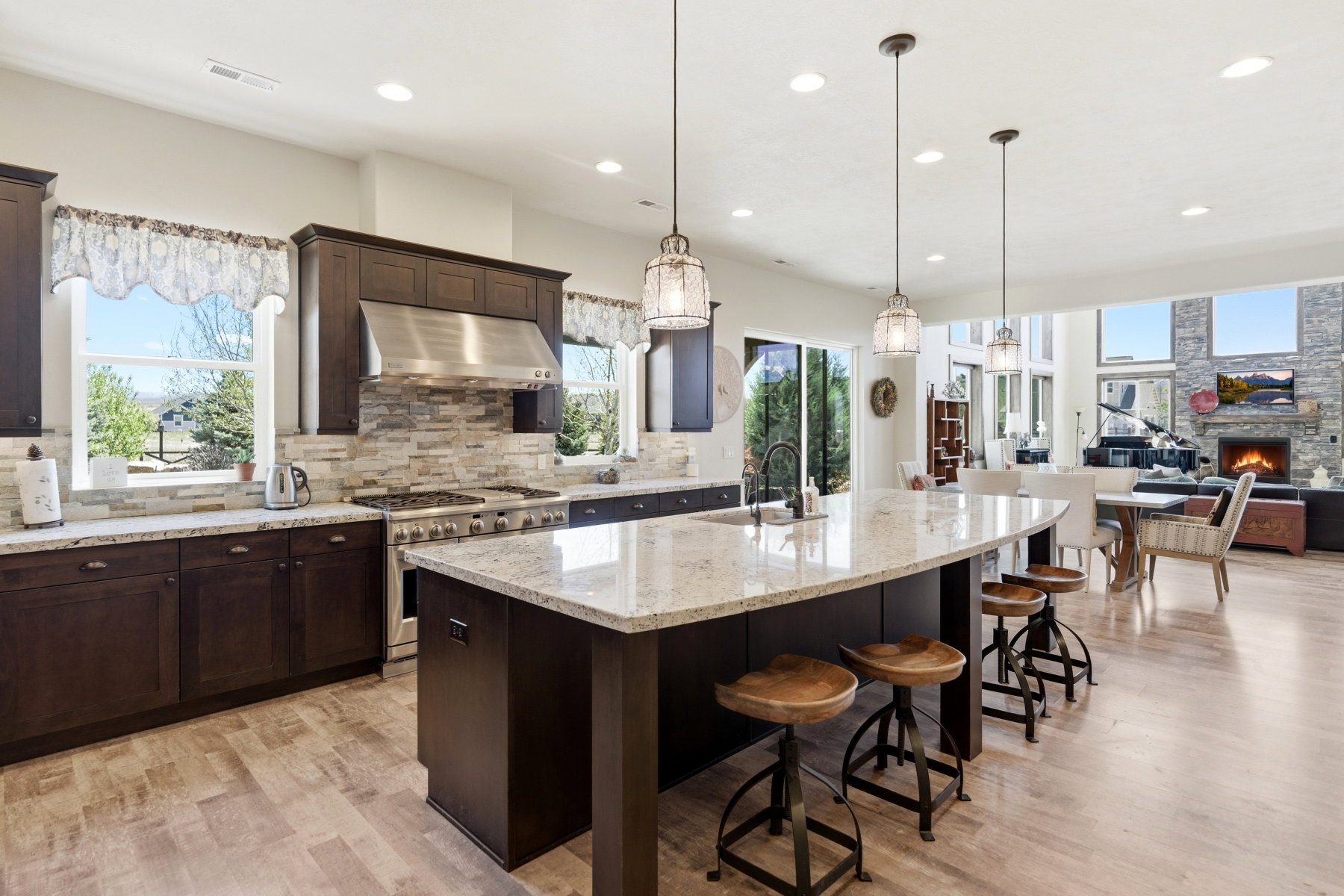 Gourmet kitchen featuring a large island with seating, stainless steel appliances, stacked stone backsplash, and granite countertops
