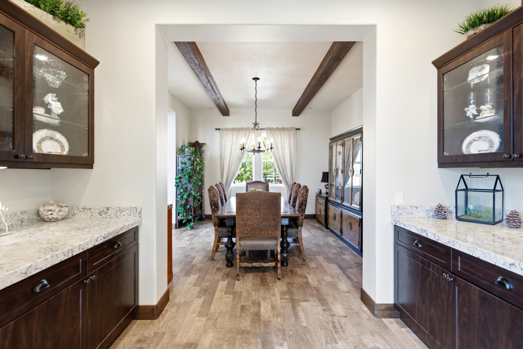 Inviting dining space featuring wood-finish flooring, exposed ceiling beams, and a chandelier lighting fixture
