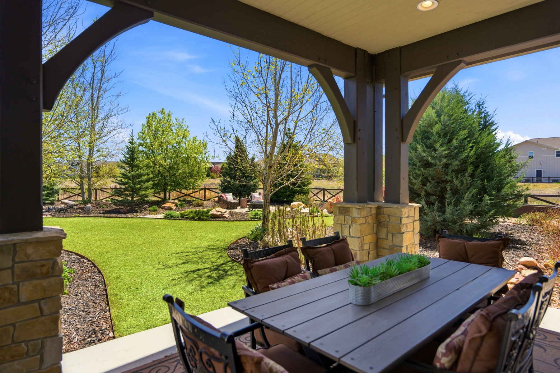 Covered patio featuring robust wood beams and stone-clad pillars