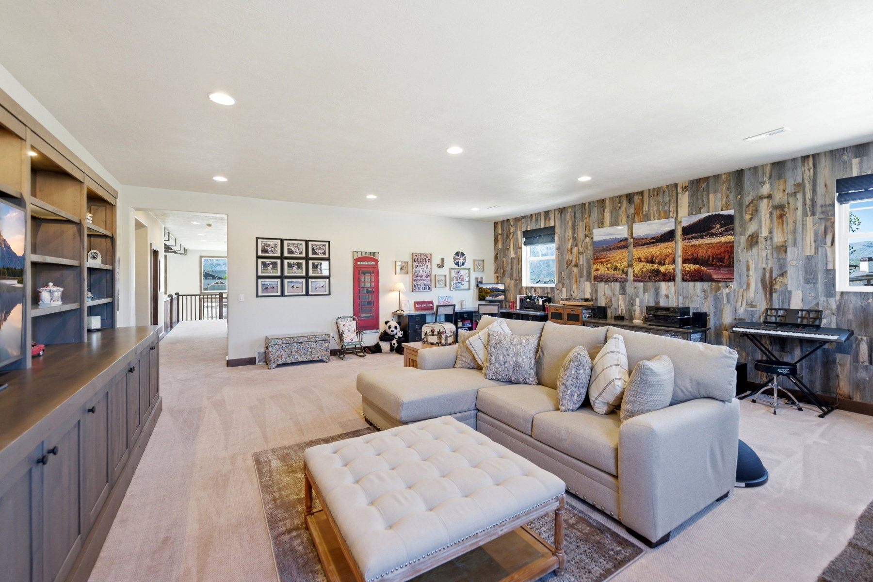 Spacious living area featuring a wood-finish accent wall, built-in media cabinetry, recessed lighting, and carpeted flooring