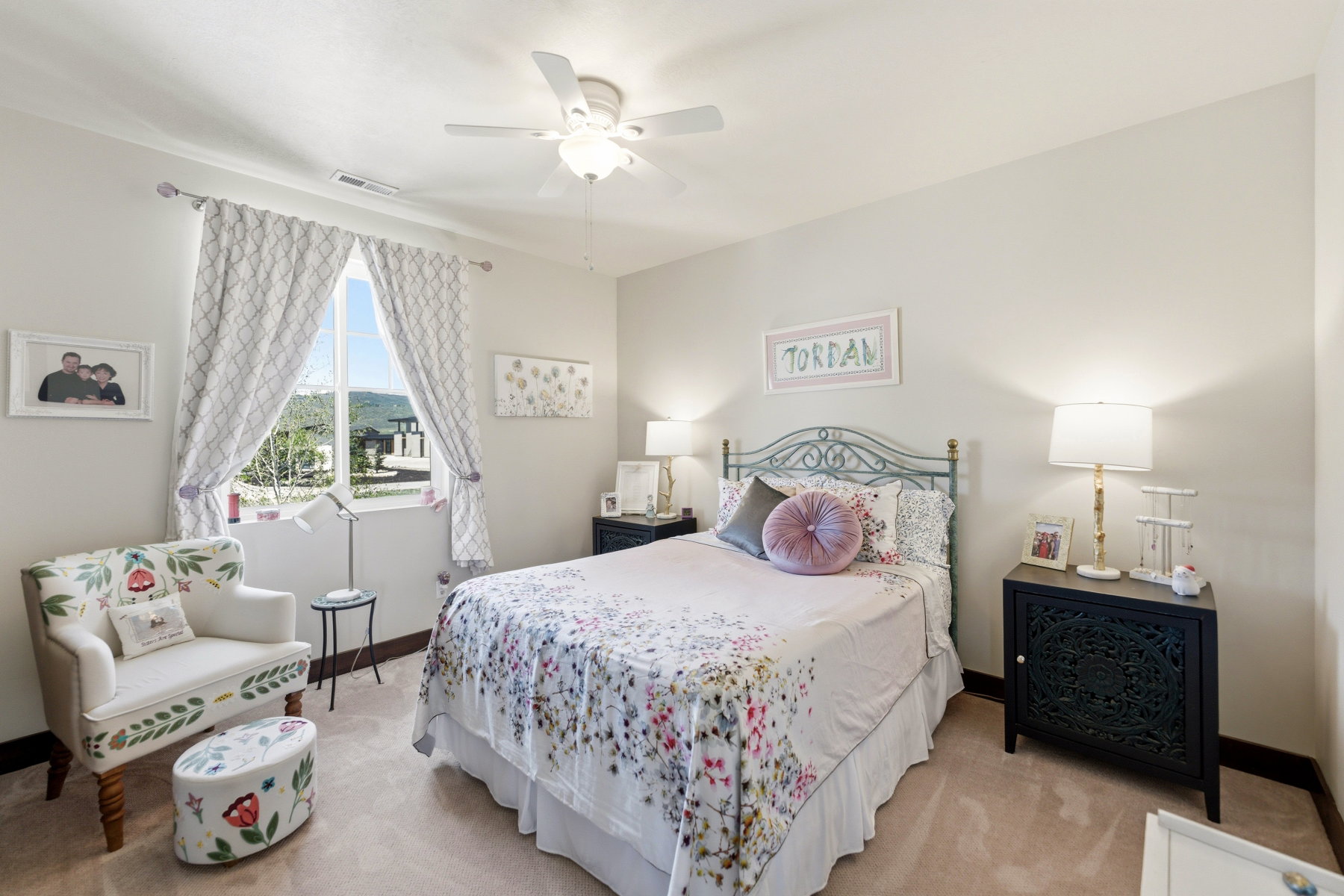 Bright bedroom featuring a ceiling fan, a large window, light-colored walls, and neutral carpeting